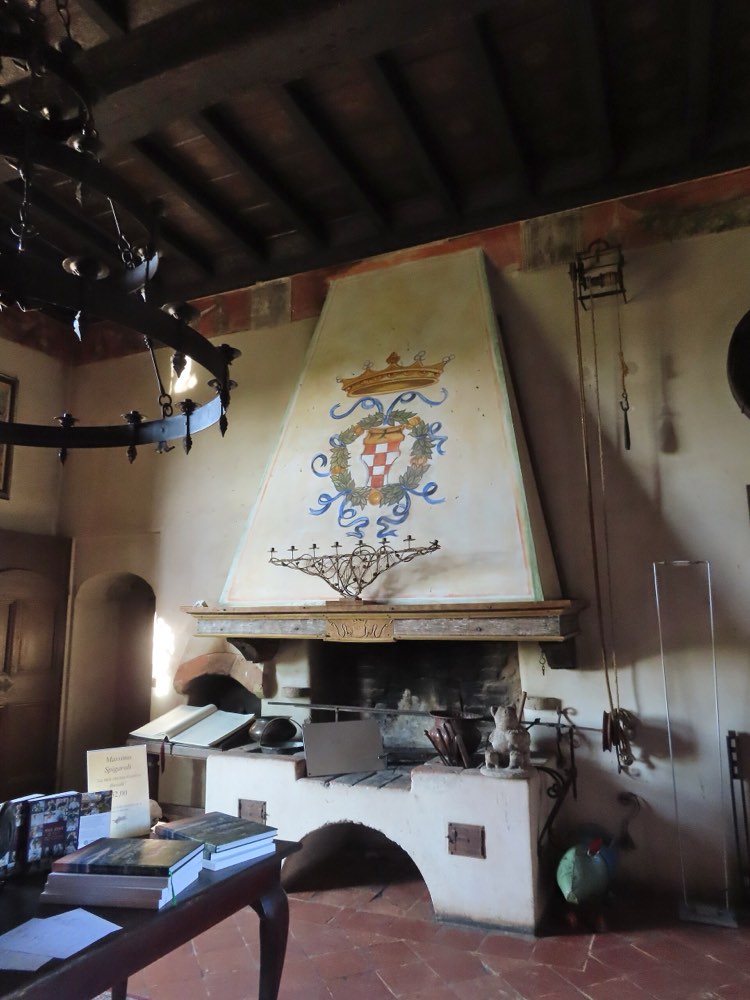 The entrance hall of Antica Corte Pallavicina, with a painted coat of arms above the fireplace