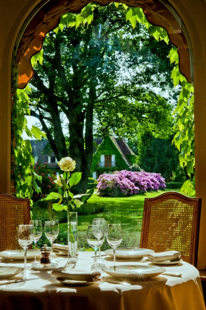 A laid table at Auberge des Templiers in Boismorand, looking through an arched window to the garden