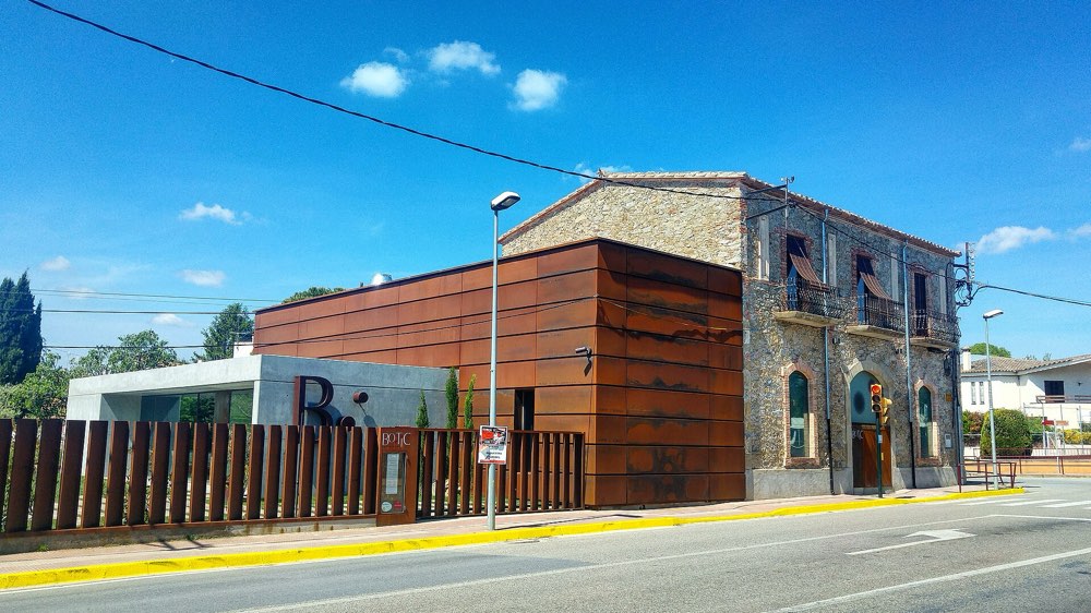 The stone house and rusted steel extension of Bo.TiC in Corçà