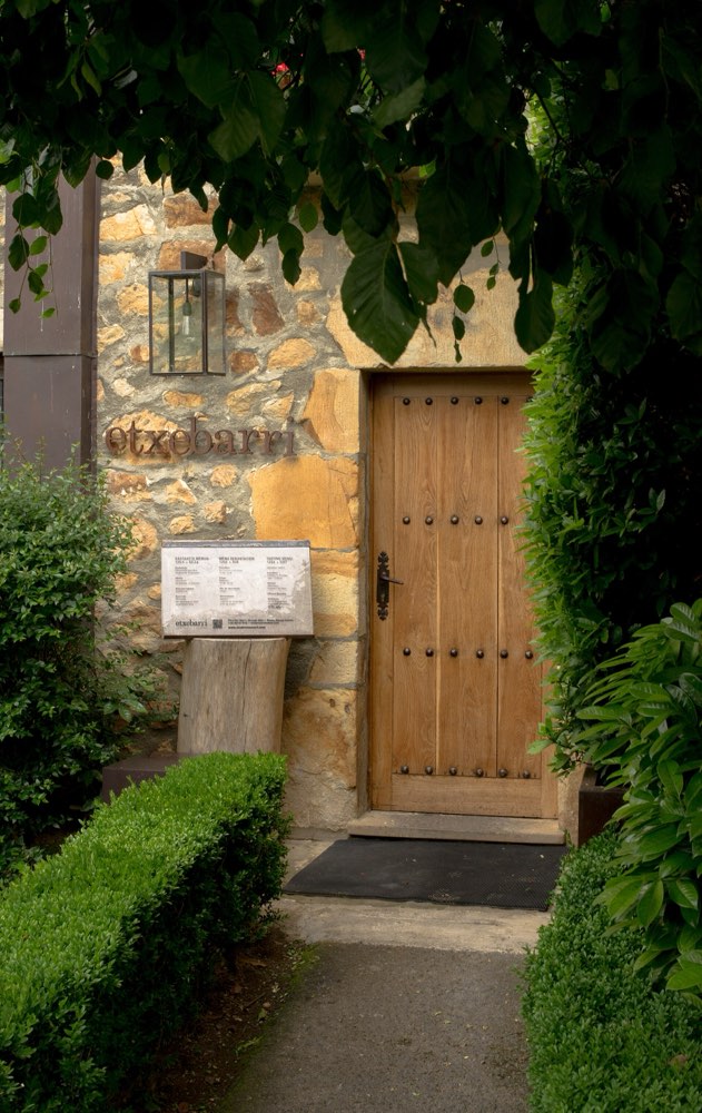 The wooden door of Asador Etxebarri in Axpe, with its name on the stone wall