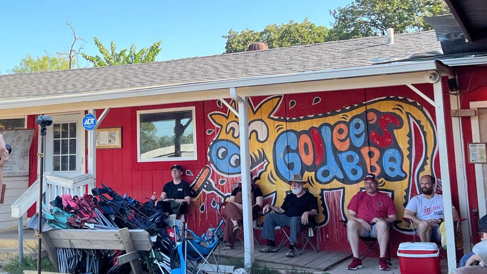 Customers waiting outside the red Goldee's building with its painted mural in Fort Worth, Texas