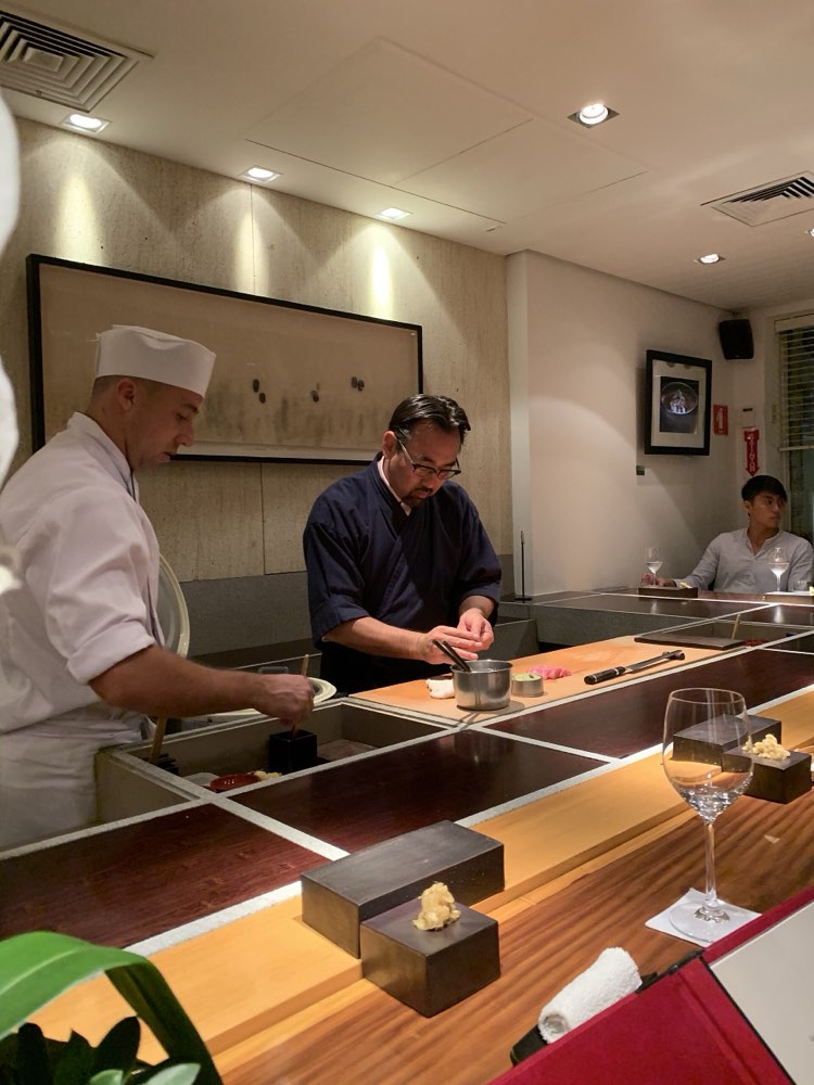 Chefs behind the wooden sushi counter at Jun Sakamoto in São Paulo