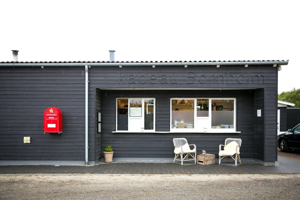 The dark timber building of Kadeau Bornholm with its name on the wall, Bornholm
