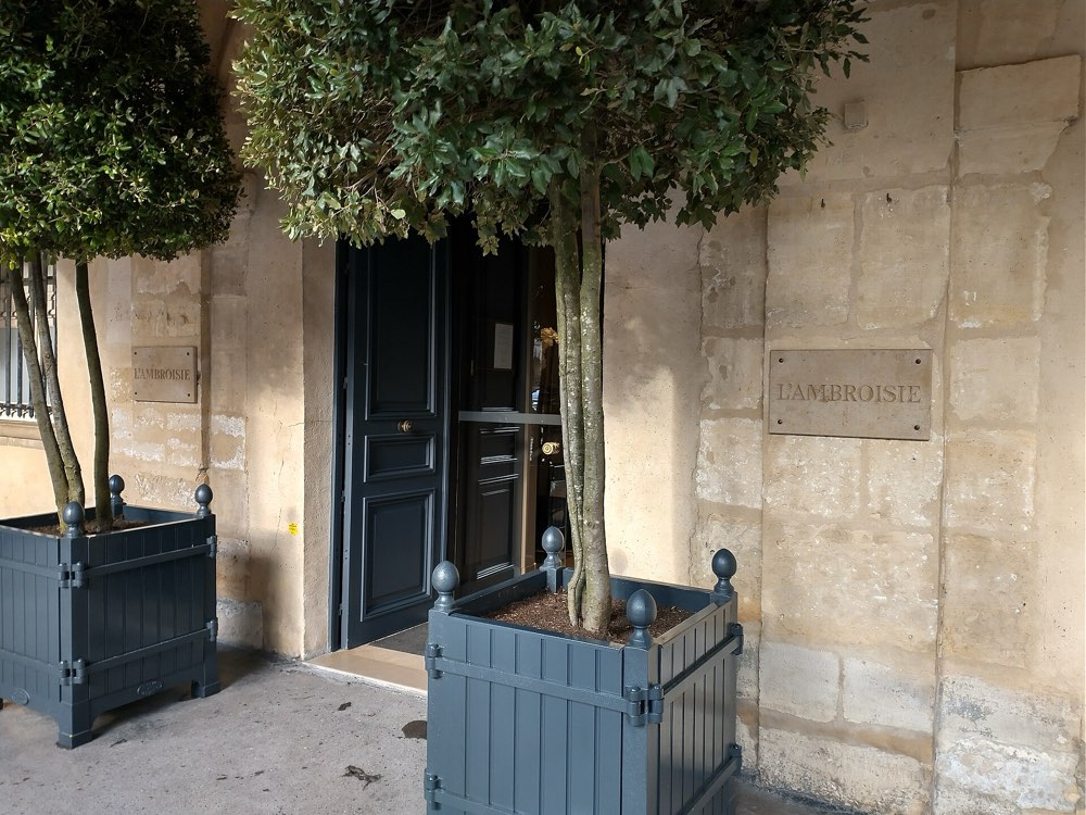 The door of L'Ambroisie on the Place des Vosges, Paris, with its name plaque on the stone wall