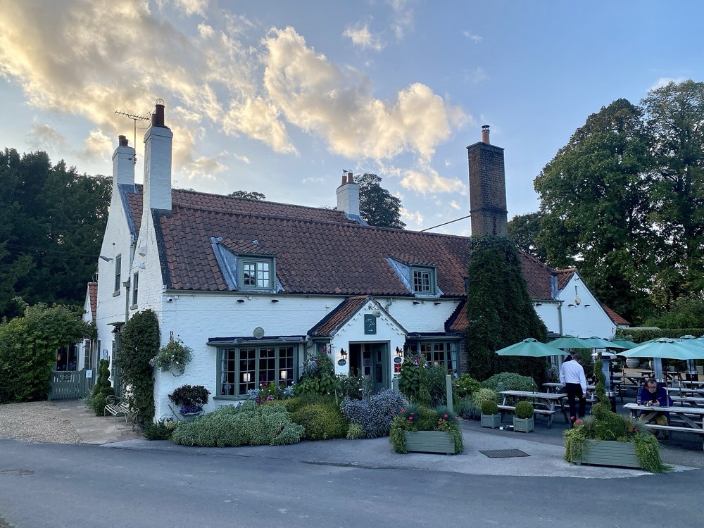 The whitewashed front and garden tables of the Pipe and Glass in South Dalton
